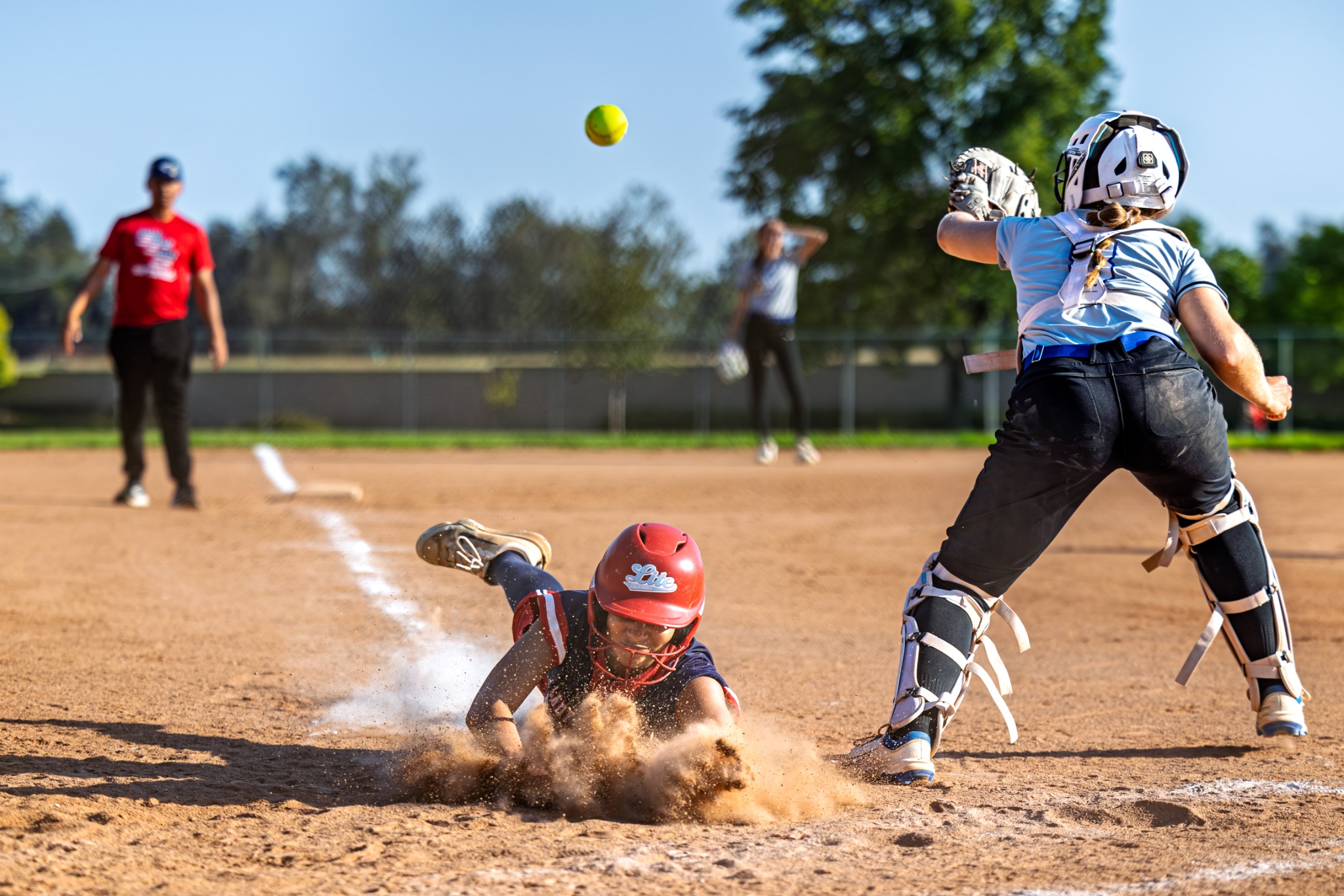 Softball player sliding into home plate