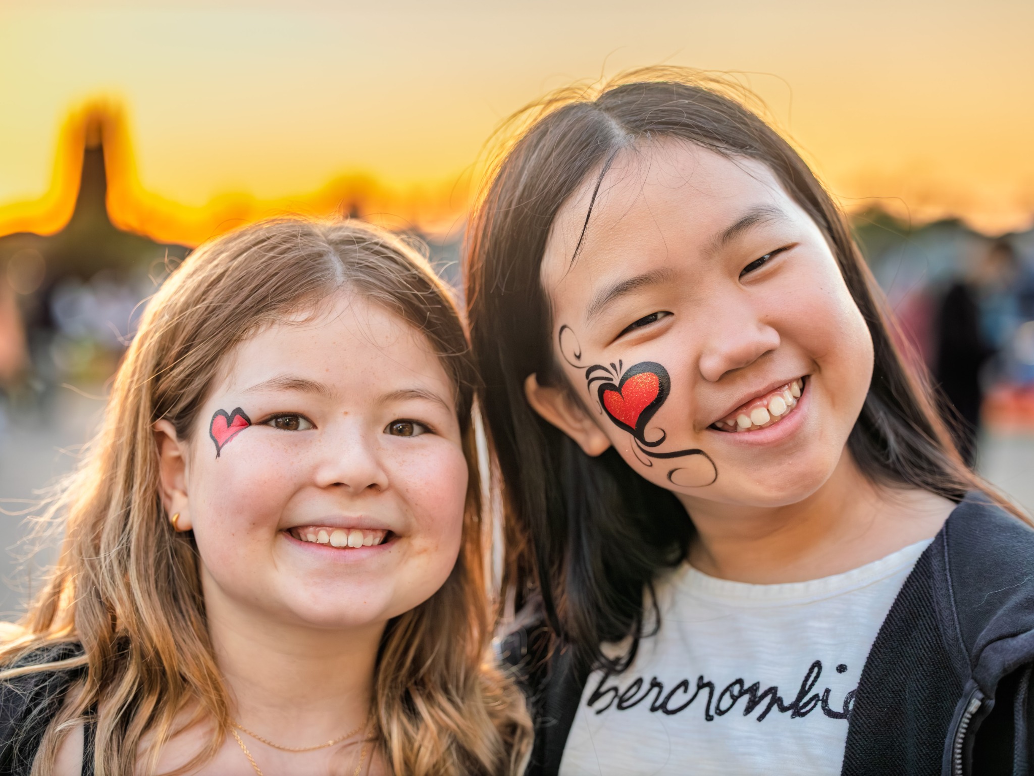 Two girls smiling with face paint at sunset
